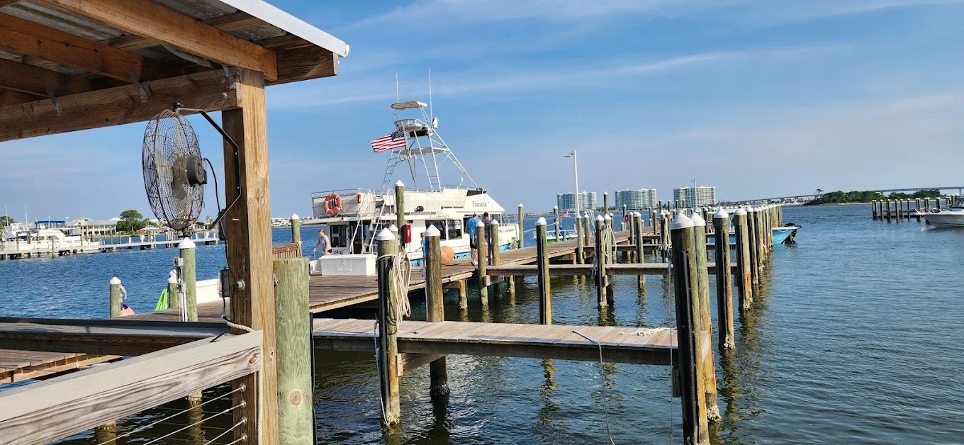 Dock with boats on a sunny day, American flag on a boat, clear blue sky.